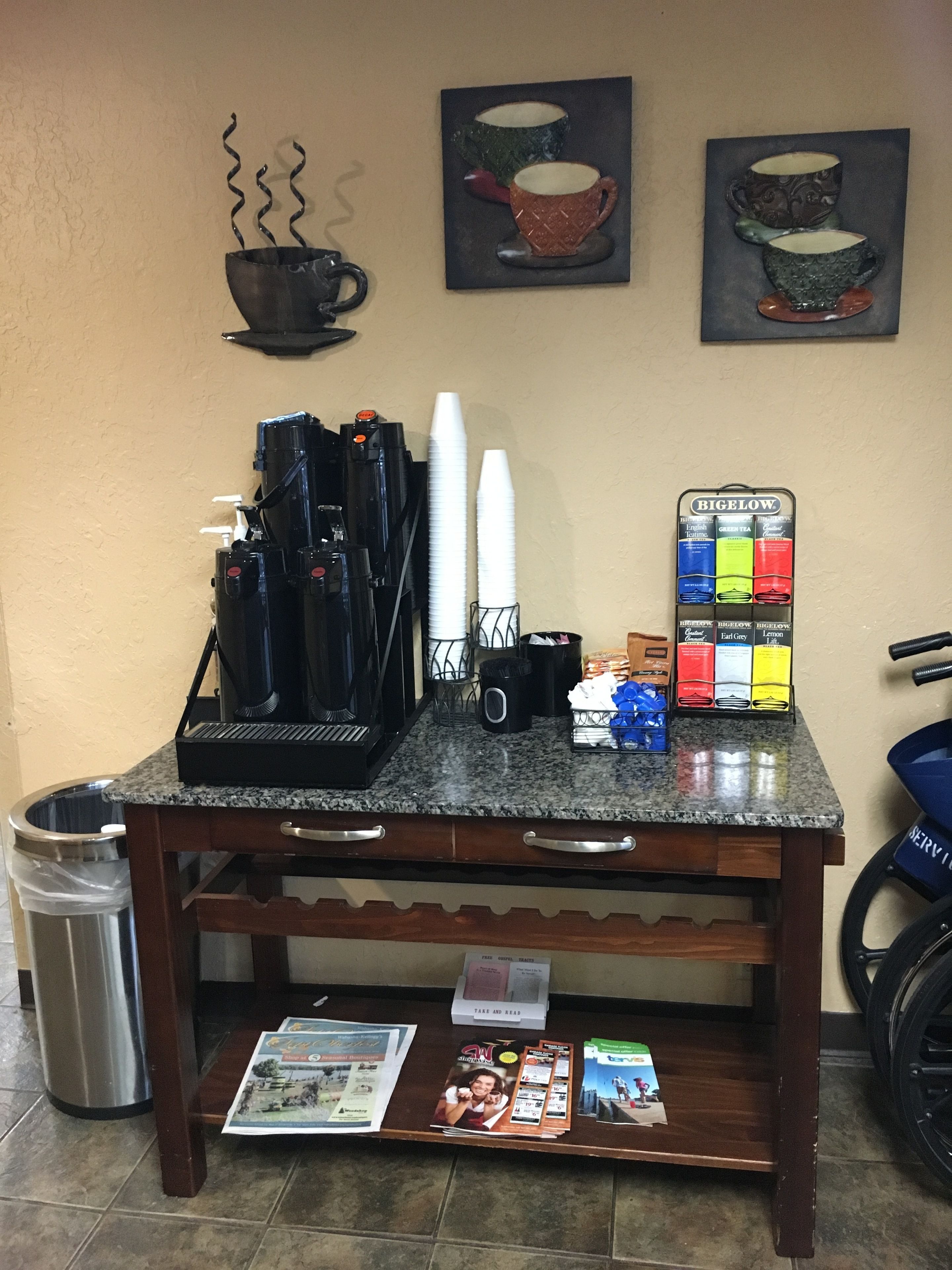 A coffee station with a coffee machine, cups, and a Bigelow tea display.