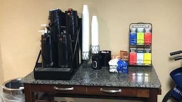 A coffee station with a coffee machine, cups, and a Bigelow tea display.