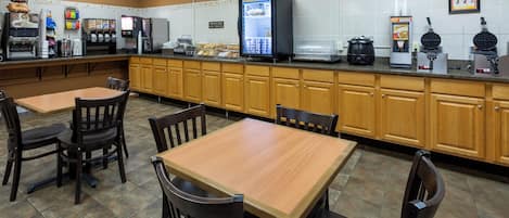A restaurant with a self-service breakfast bar, seating area, and waffle station.