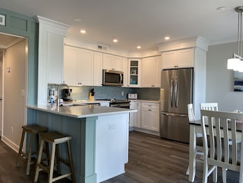 A compact kitchen with white cabinets, a microwave, a coffee maker, and a sink. There is a small dining area with a table and a green sofa. at Hilton Head Island Beach & Tennis Resort