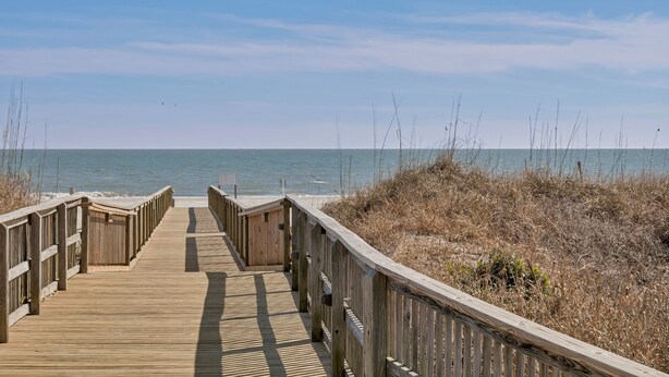 Une promenade en bois qui mène à la plage et offre une vue dégagée sur l’océan.