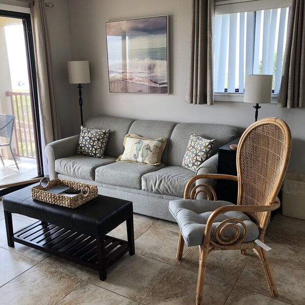 A living room with a grey sofa, patterned cushions, a wicker chair, a black coffee table, and a woven basket. - Hilton Head Island Beach & Tennis Resort (Hilton Head Island)