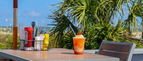 An outdoor table with a white umbrella labeled "TRULY" and a drink.