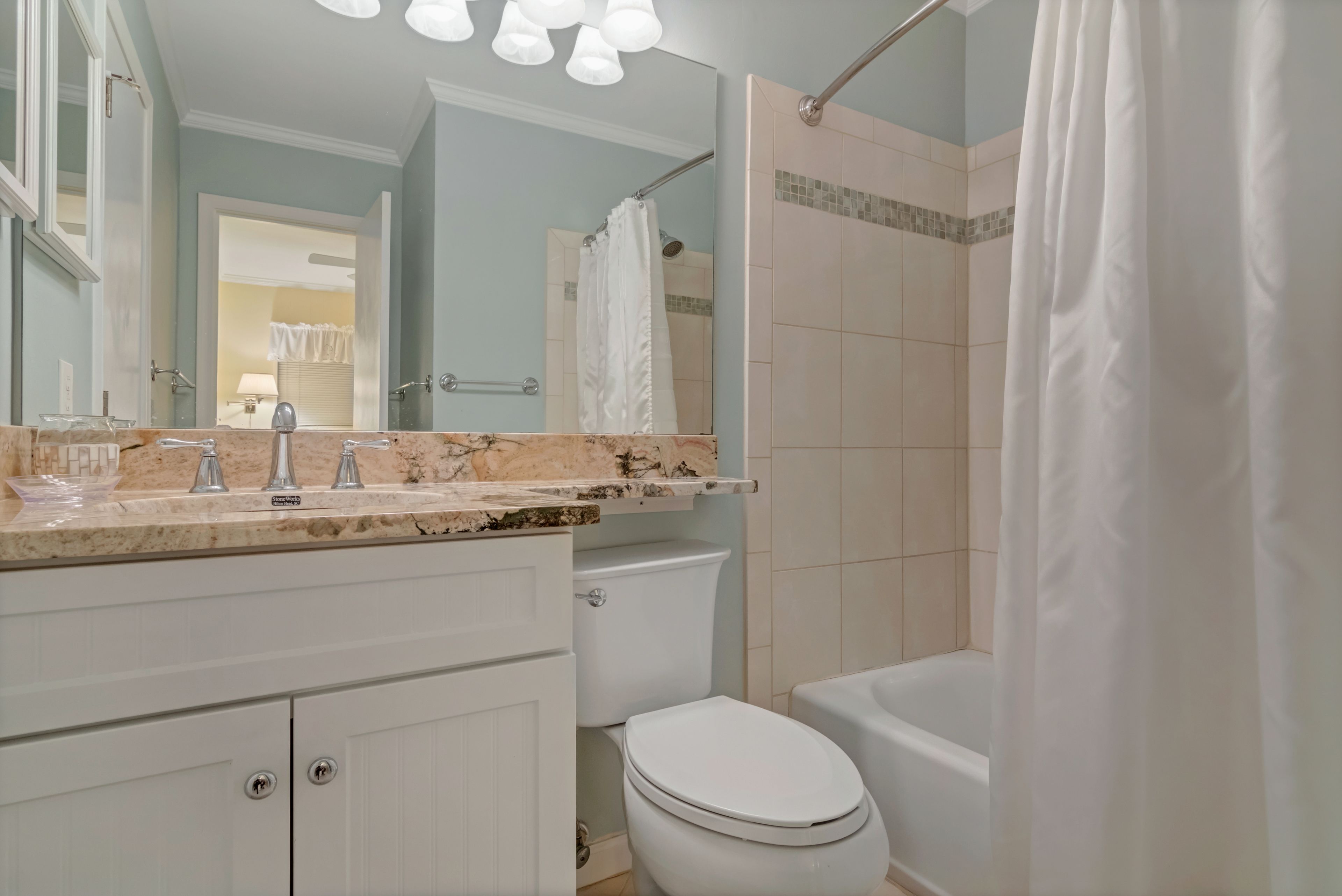 Une salle de bain avec un comptoir en marbre, des toilettes, une baignoire et un rideau de douche.