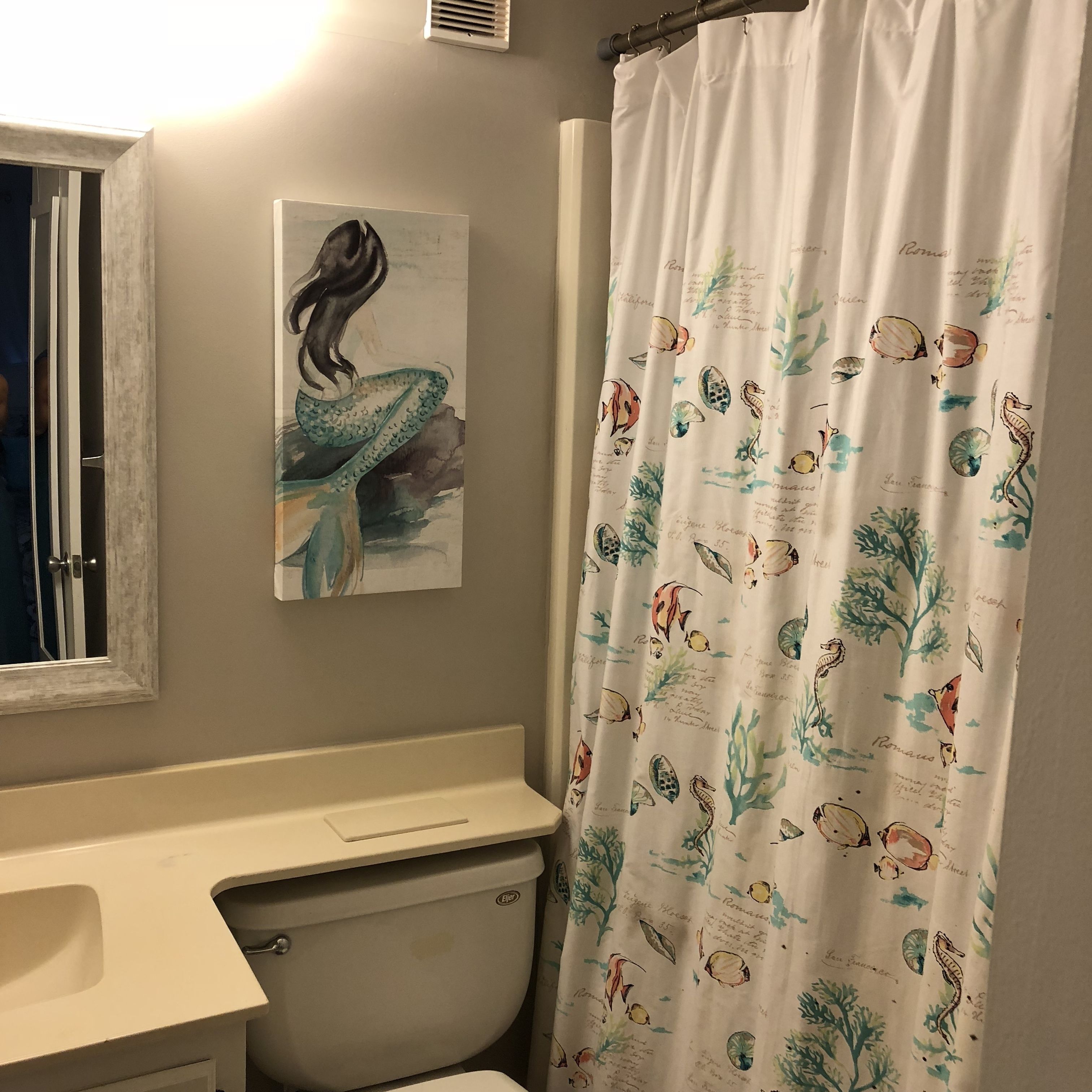 A bathroom with a toilet, a sink, and a shower curtain with marine life illustrations.