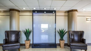 Un hall con dos sillones de cuero, una fuente de agua y plantas en macetas.