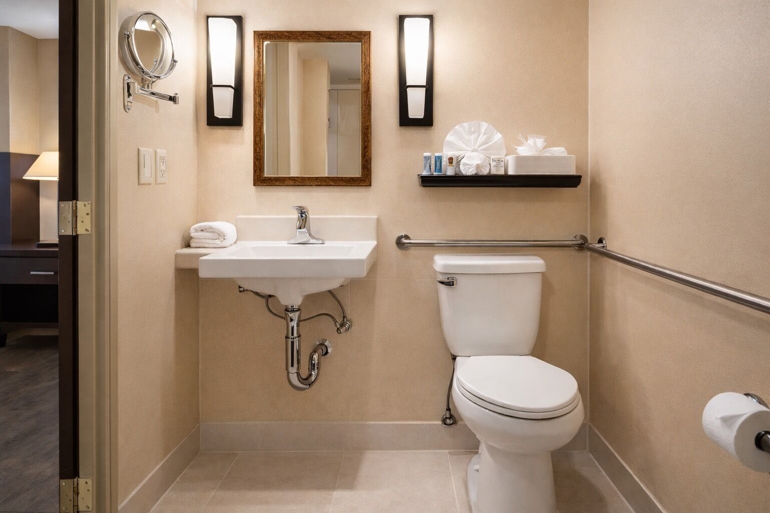 A small bathroom with a sink, toilet, and a mirror. There is a towel on the sink and toiletries on a shelf.