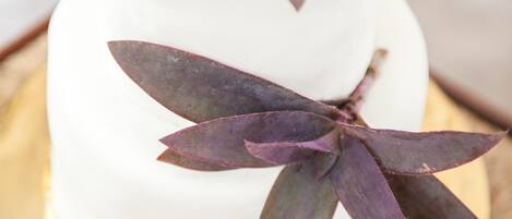 A white cake with purple leaves on a golden plate.
