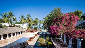 Un resort con piscina, palmeras y un árbol de flores rosadas.