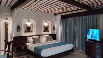 Una habitación de hotel con una cama grande, un televisor y un adorno en la pared.