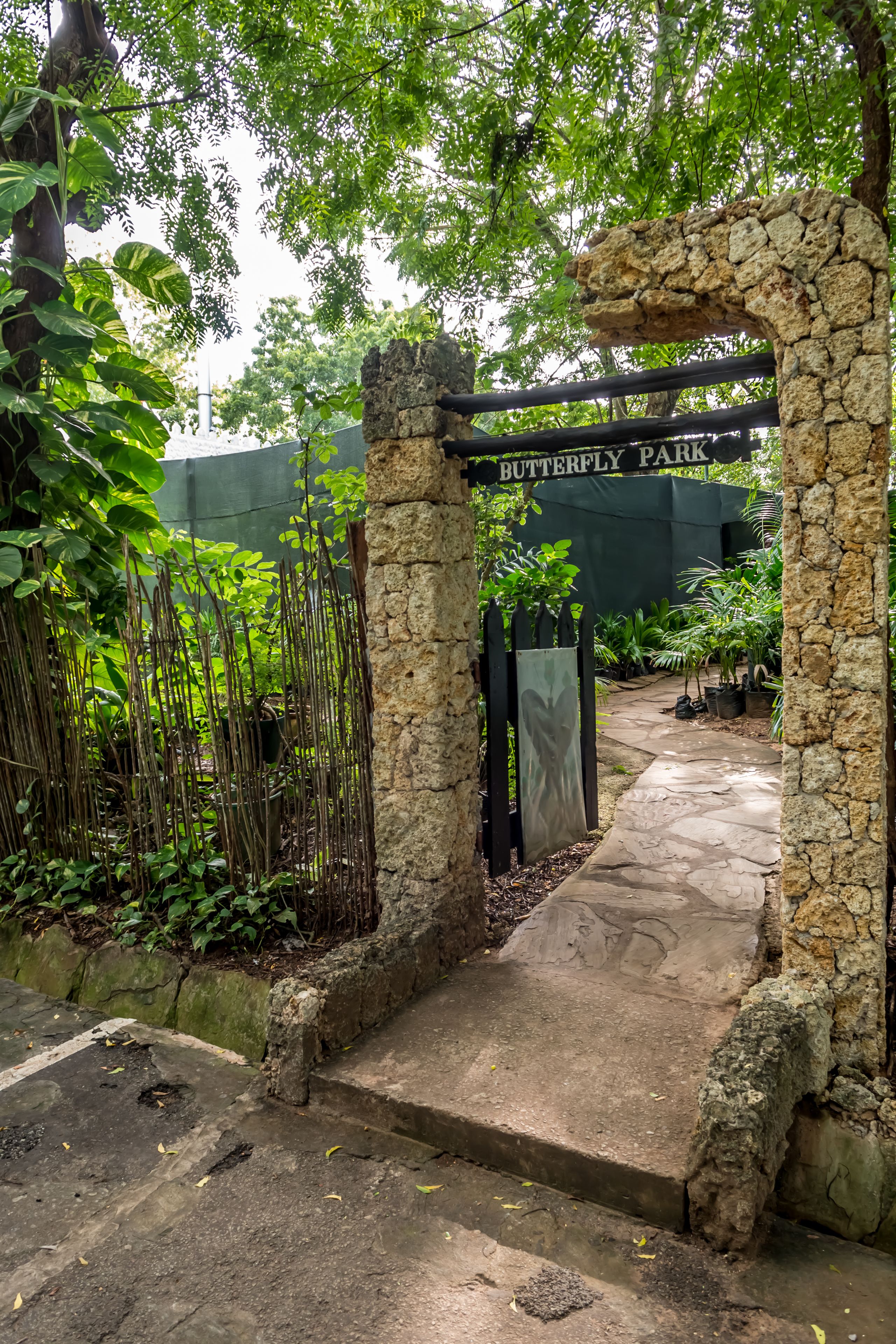 A stone archway leading to Butterfly Park with a stone pathway and lush greenery.