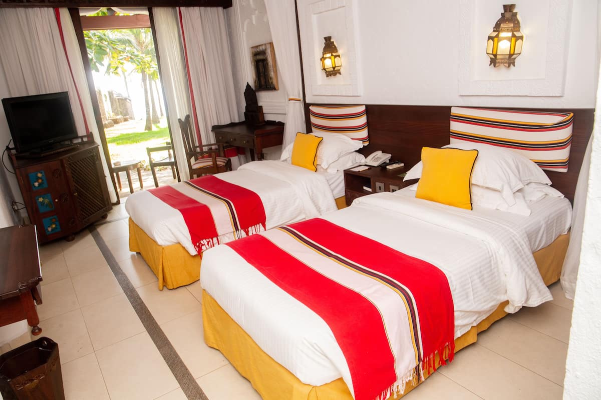 A hotel room with two beds, a television, a desk, and a chair.
