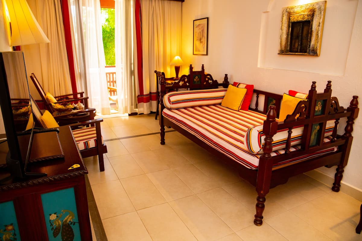 A traditional wooden bed with striped bedding, a wooden nightstand, a chair, and a lamp.