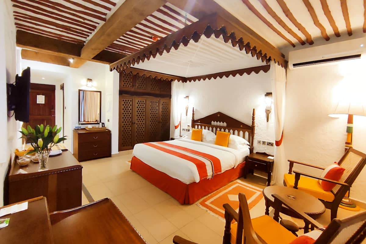 A hotel room with a large bed, wooden furniture, a television, and a desk.