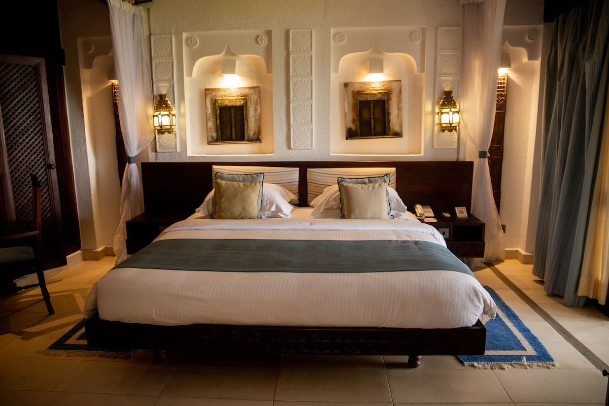 A large bed with a wooden frame, two bedside tables, and wall-mounted lamps.