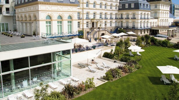 A hotel courtyard with outdoor seating, a glass building, and classic European architecture. - Hotel de France (St. Saviour)