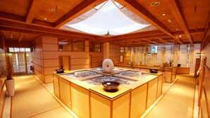 A traditional Japanese-style interior with tatami flooring, a central tatami mat table with a decorative bowl, wooden beams, and sliding doors. - Hotel de France (St. Saviour)
