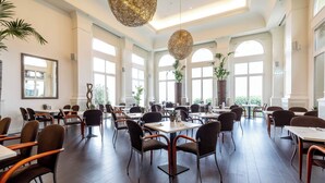 A spacious dining area with high ceilings, large windows, and modern furniture. - Hotel de France (St. Saviour)