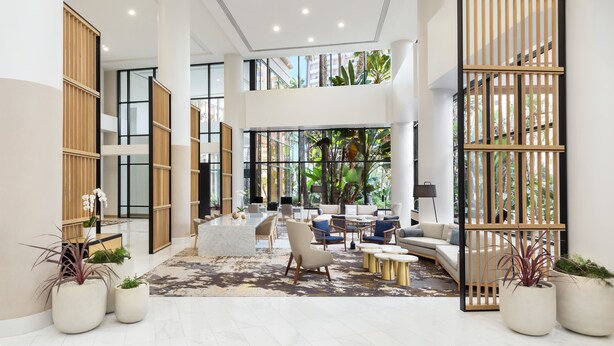 Un vestíbulo amplio con techo alto, muebles modernos y ventanas grandes que dan a vistas de follaje.