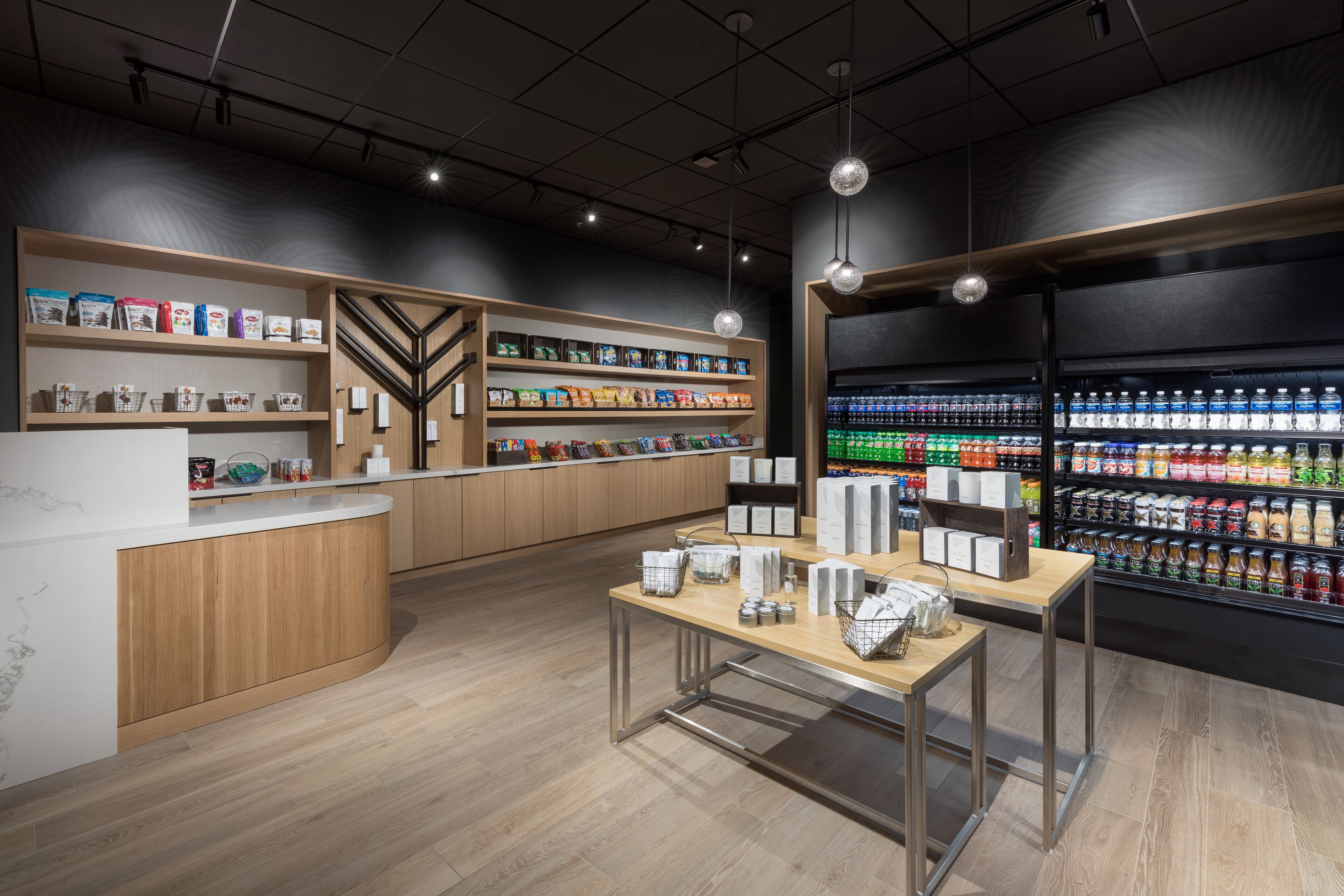 A modern retail store with wooden shelving, a central counter, and a refrigerated section.