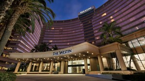 Un hotel moderno con fachada curva, palmeras y un llamativo letrero de "The Westin".