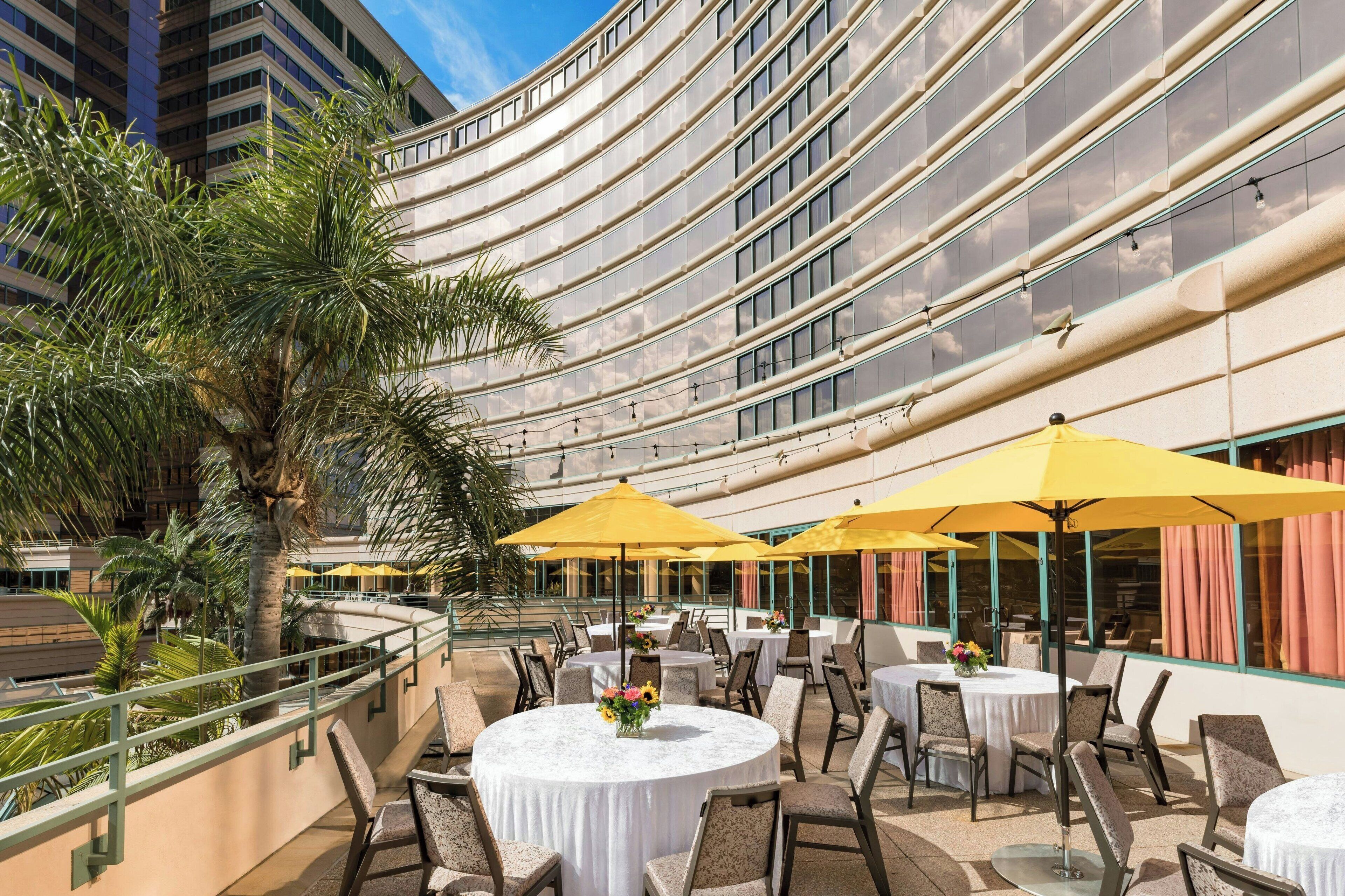 Un espace extérieur aménagé pour les repas, avec des tables rondes, des parasols jaunes et des chaises.
