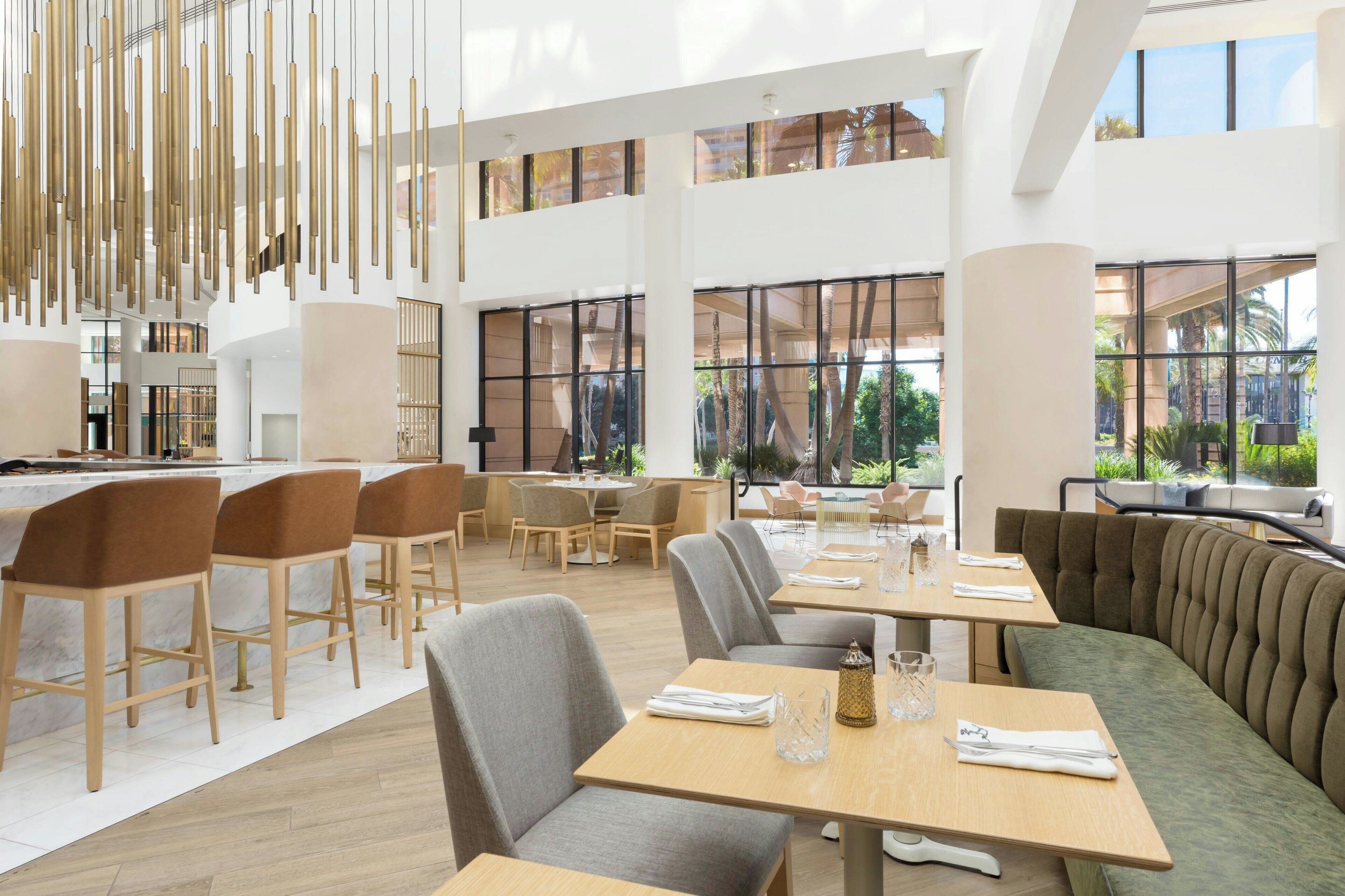 En rummelig restaurant med højt til loftet, moderne møbler og store vinduer med udsigt til det fri.