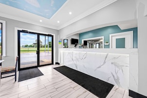 A modern reception area with a marble wall, a reception desk, and a view of the outdoors.
