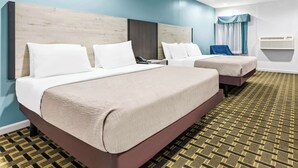 Une chambre d’hôtel avec deux lits, une tête de lit en bois, une moquette à motifs et une fenêtre avec des rideaux.