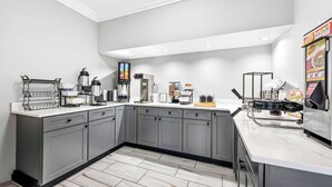 Une cuisine moderne avec des meubles gris, un plan de travail blanc et divers appareils, notamment une machine à café et un grille-pain.
