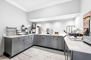 A modern kitchen with grey cabinets, a white countertop, and various appliances including a coffee machine and a toaster.
