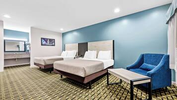 Habitación de hotel con una cama, dos mesitas de noche, una silla, un escritorio, un espejo y un cuadro en la pared.