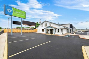 A parking lot with a SureStay by Best Western sign, a white building with a garage, and a clear blue sky.