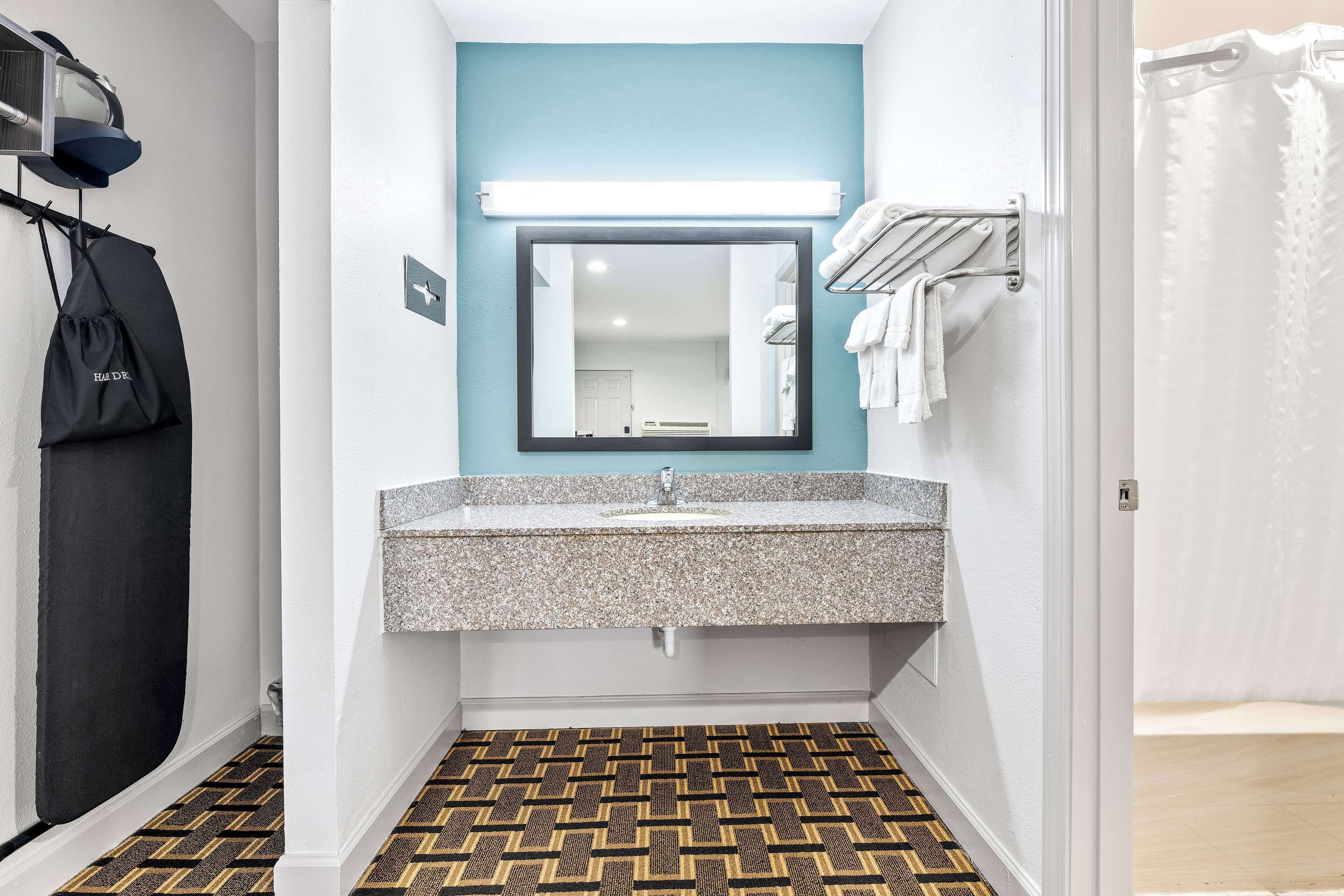 Une salle de bain avec un lavabo surmonté d’un plan de travail en granit, un miroir et un carrelage décoratif.