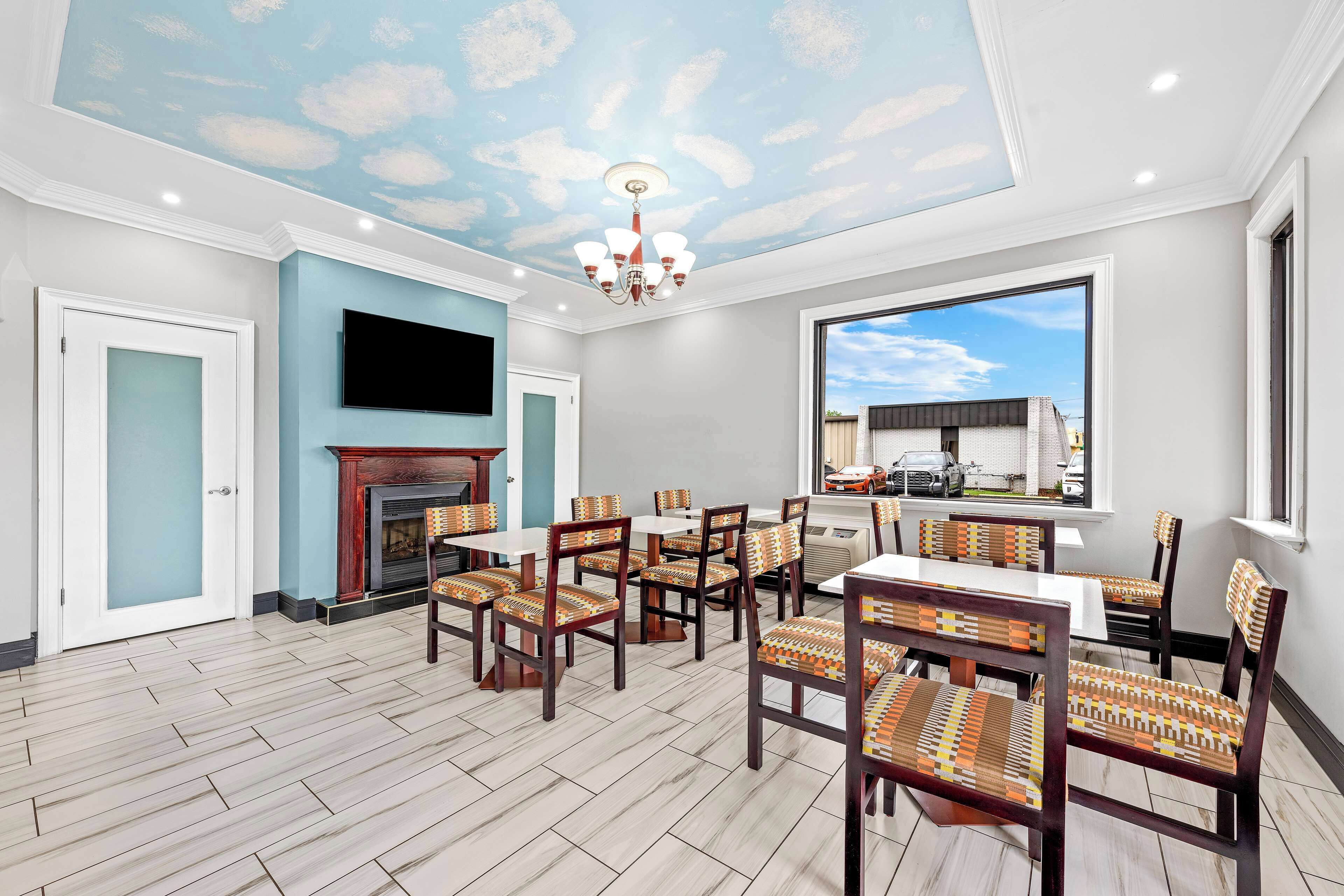 A dining area with a fireplace, wooden chairs, and a large window.