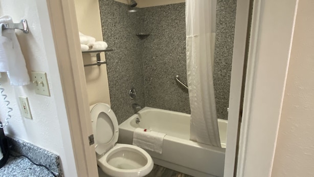 A bathroom with a toilet, bathtub, and shower curtain. - Days Inn by Wyndham Pearl/Jackson Airport (Pearl)