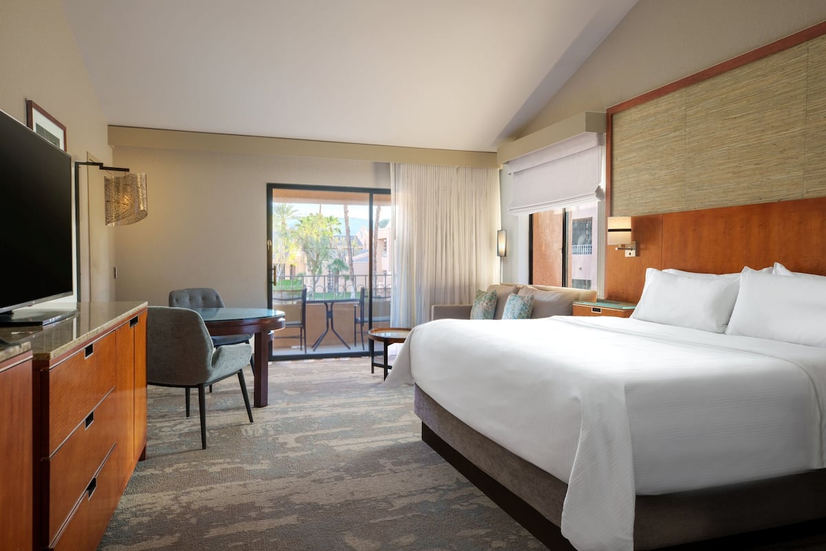 Een hotelkamer met een groot bed, een bureau, een televisie en uitzicht op de omgeving.