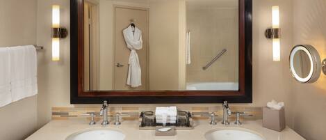 Un baño con dos lavamanos, un espejo grande, toalleros y una cabina de ducha de vidrio.