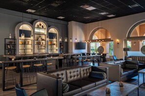 Un espace bar moderne avec des sièges en cuir, un comptoir et des étagères remplies de verres.