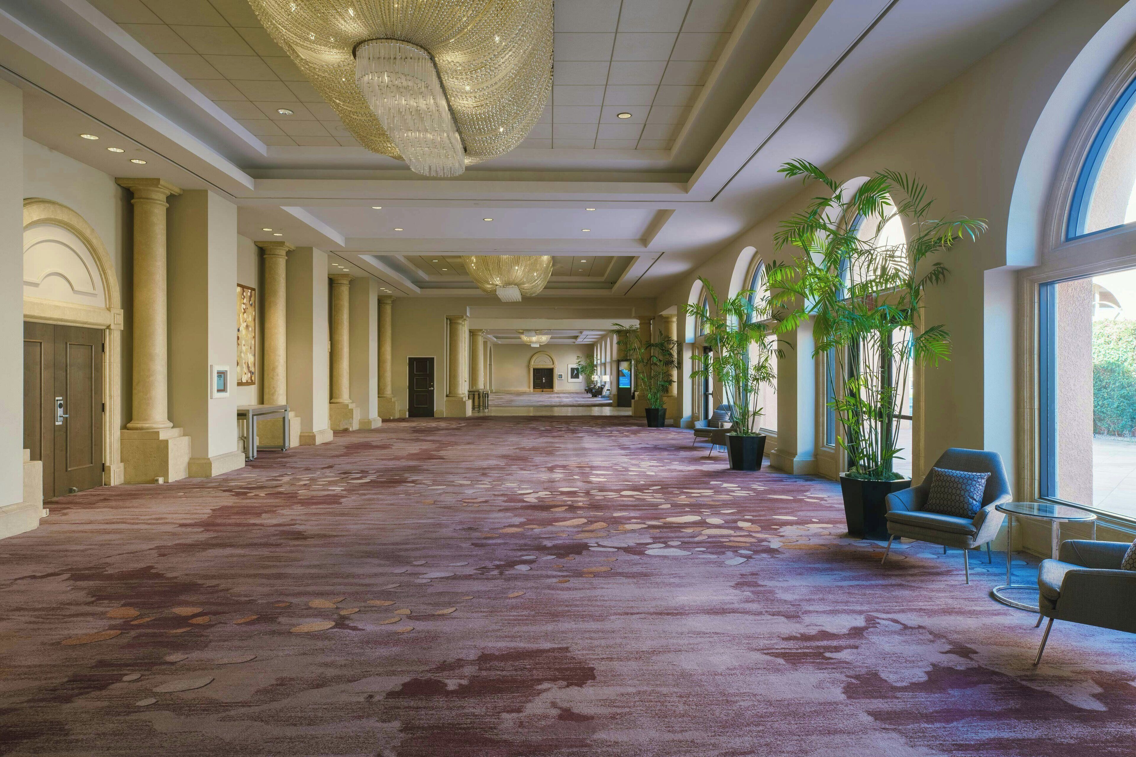 Un hall d’entrée spacieux, doté d’un tapis à motifs, de grandes colonnes et d’un lustre.