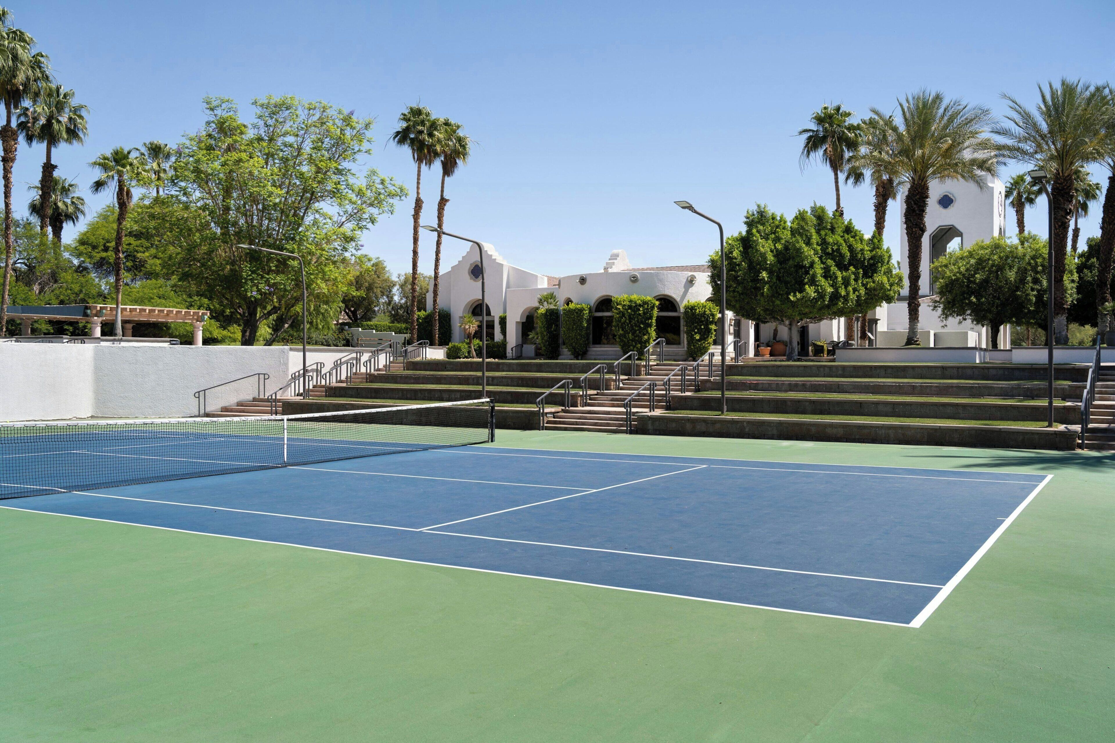 Un court de tennis avec un bâtiment blanc en arrière-plan.