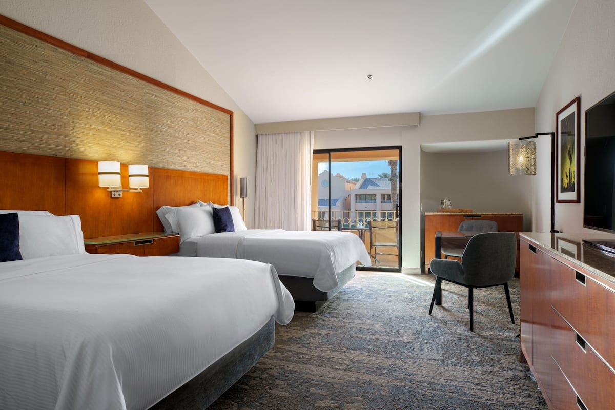 Een hotelkamer met twee bedden, een bureau, een stoel en een televisie.