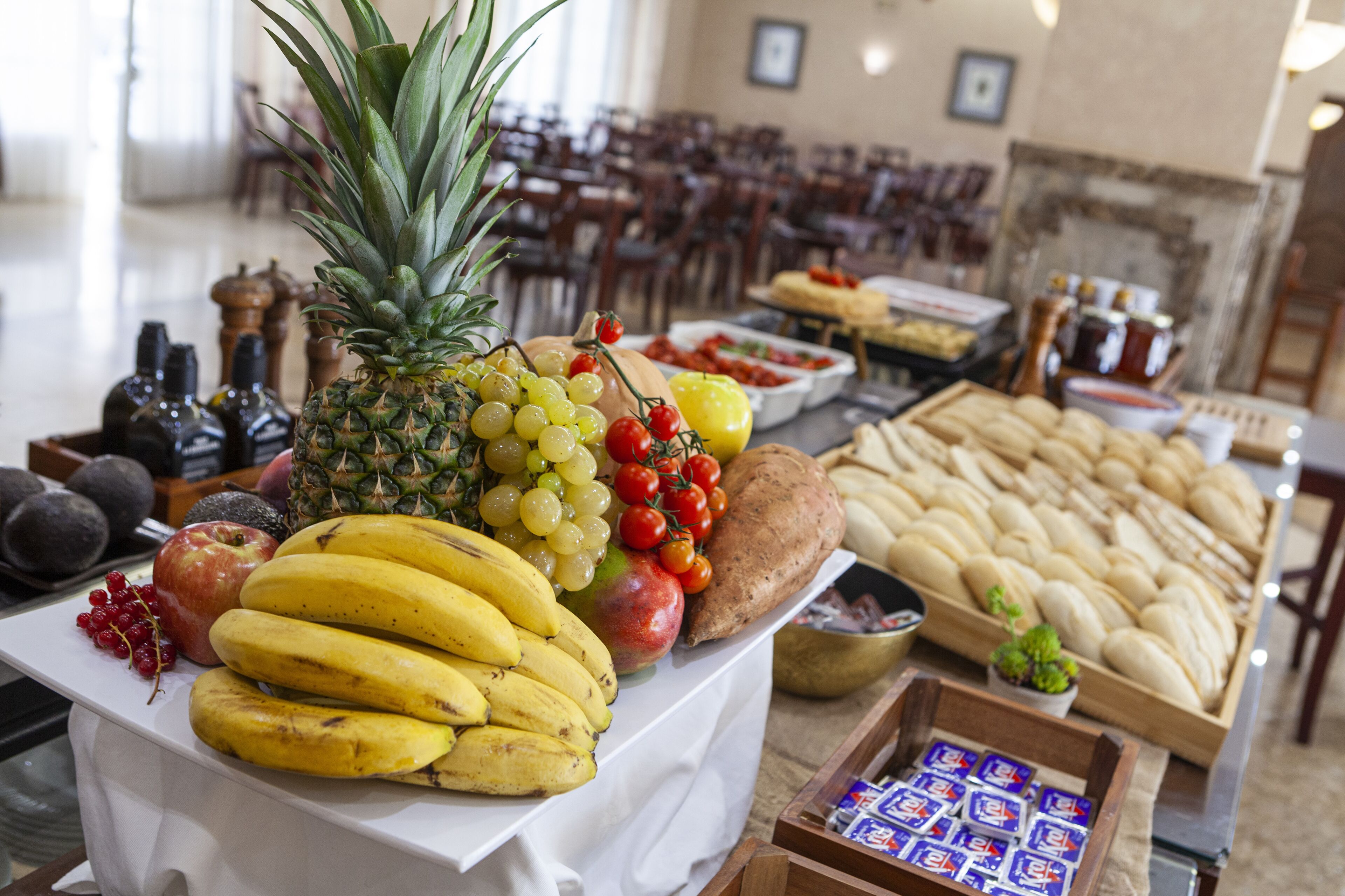 Una mesa de buffet con diversas frutas, pan y salsas.