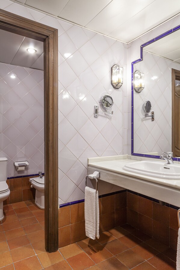A bathroom with a white tiled wall, a wooden door frame, a white sink with a mirror, and a toilet.