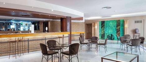 Eine moderne Hotelhalle mit Barbereich, Sitzgelegenheiten und einem großen, grünen Wandgemälde.
