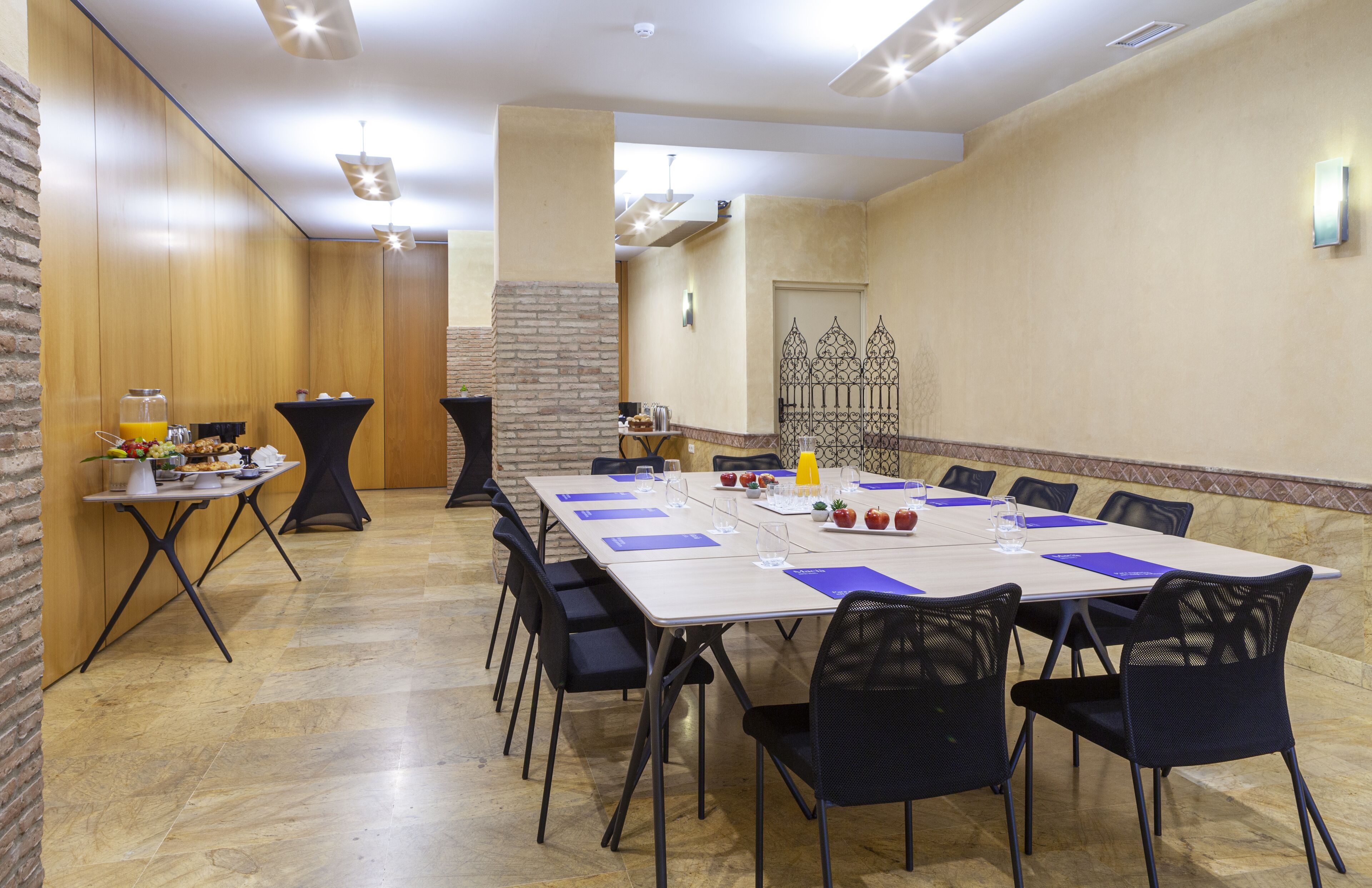 Une salle de conférence avec une longue table, des chaises noires et une table de buffet où sont disposés des plats et des boissons.