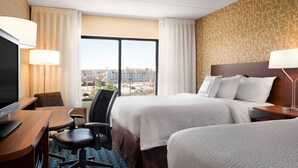 A hotel room with two beds, a desk with a TV, and a view of buildings through large windows. - Fairfield Inn by Marriott Philadelphia West Chester/Exton (Exton)