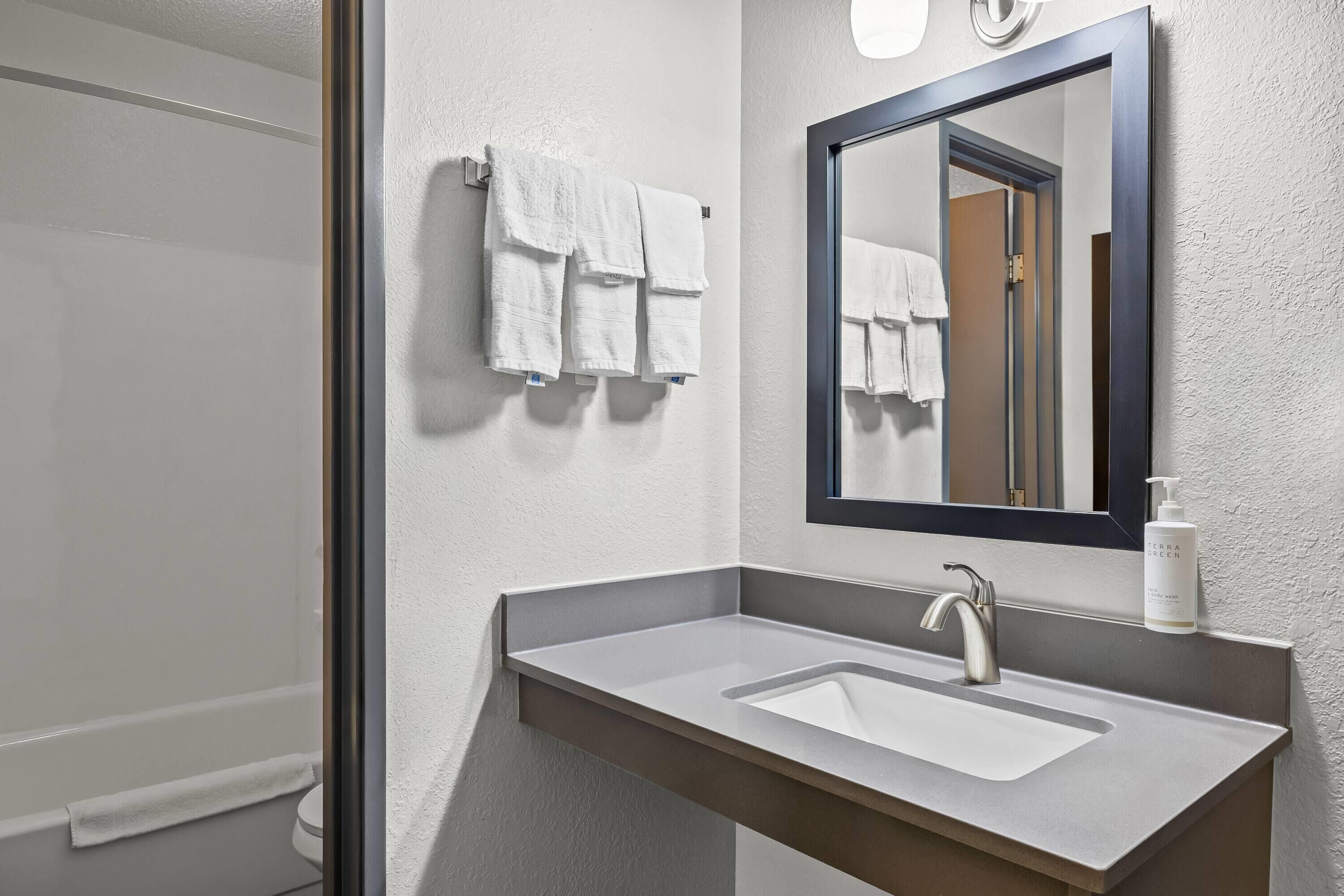 A bathroom with a sink, mirror, and towels.