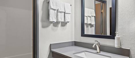 A bathroom with a sink, mirror, and towels.