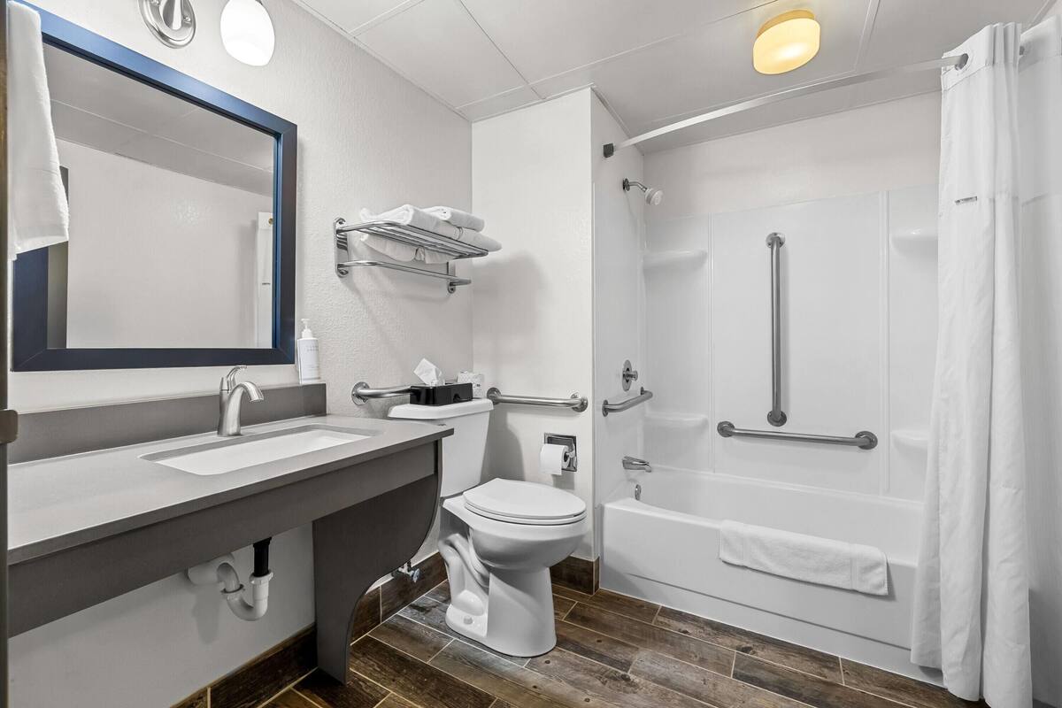 A modern bathroom with a sink, toilet, shower, and bathtub.